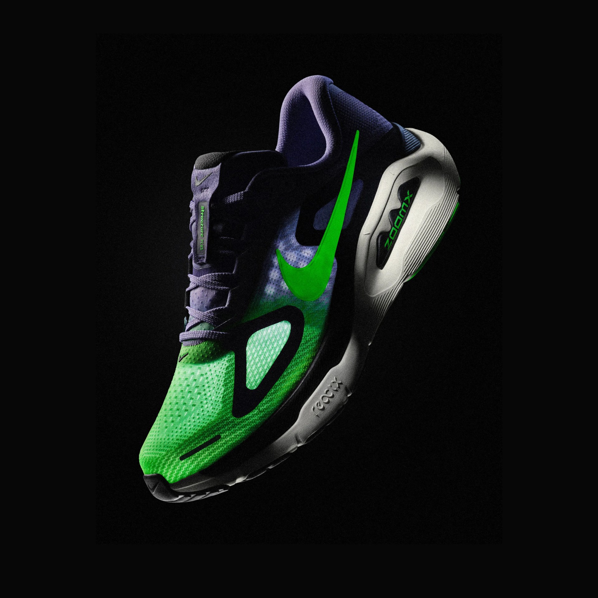 Green and purple Nike ZoomX running shoe with black accents and white sole on black background.