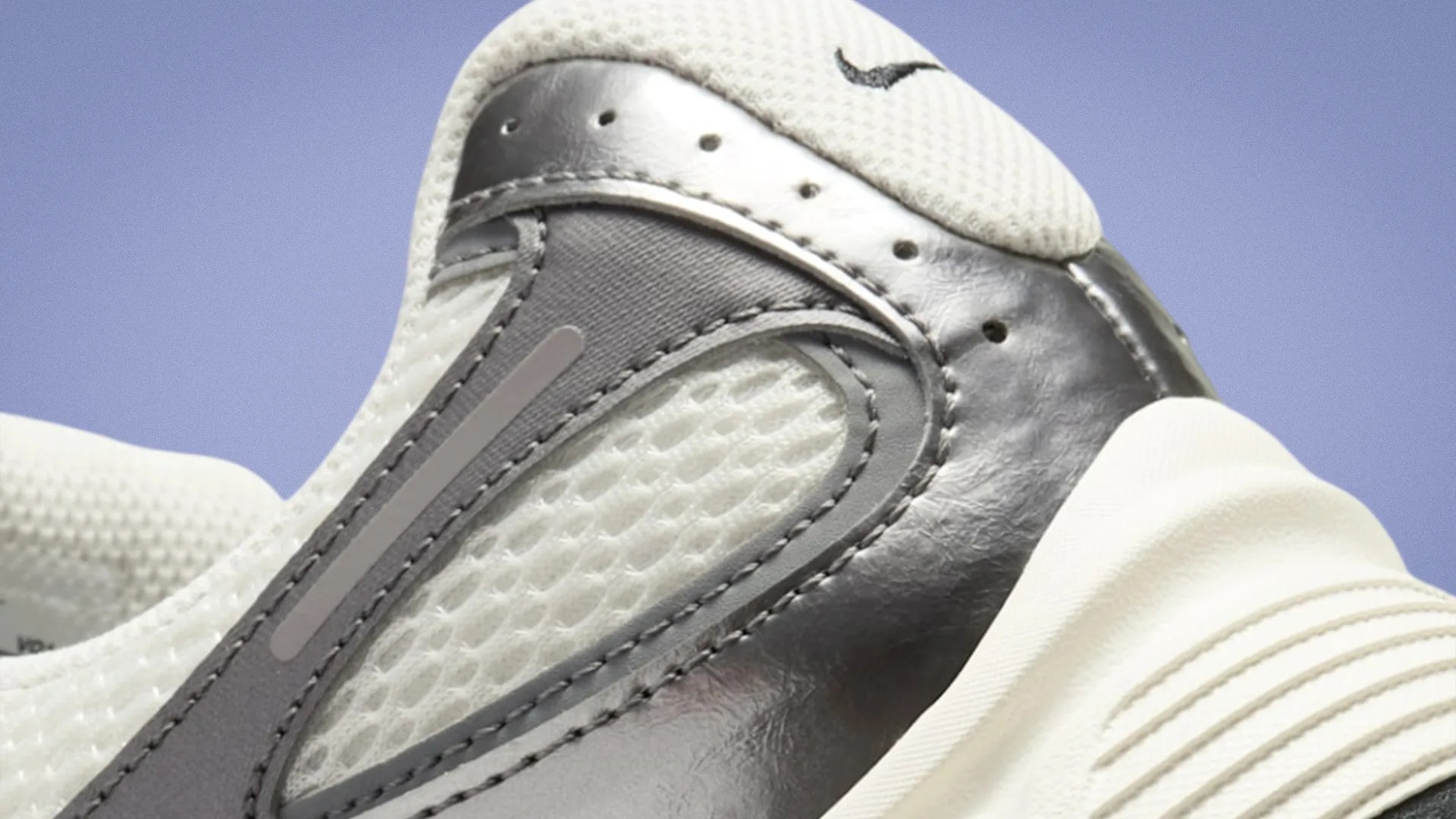 Close-up of a white and gray Nike sneaker heel with textured mesh and leather details against a blue background.