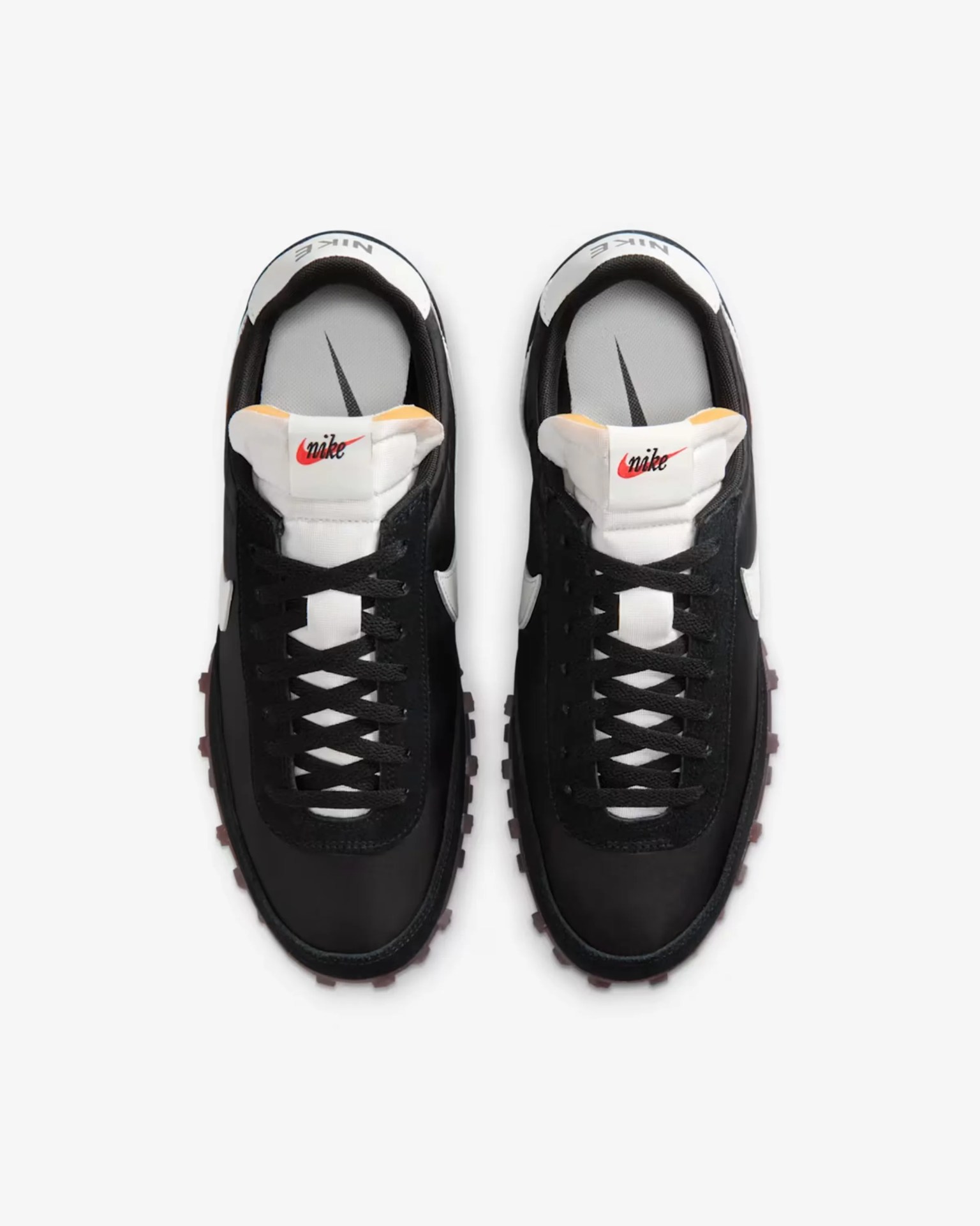 Pair of black and white Nike sneakers with black laces and red logo on white tongue, viewed from above.