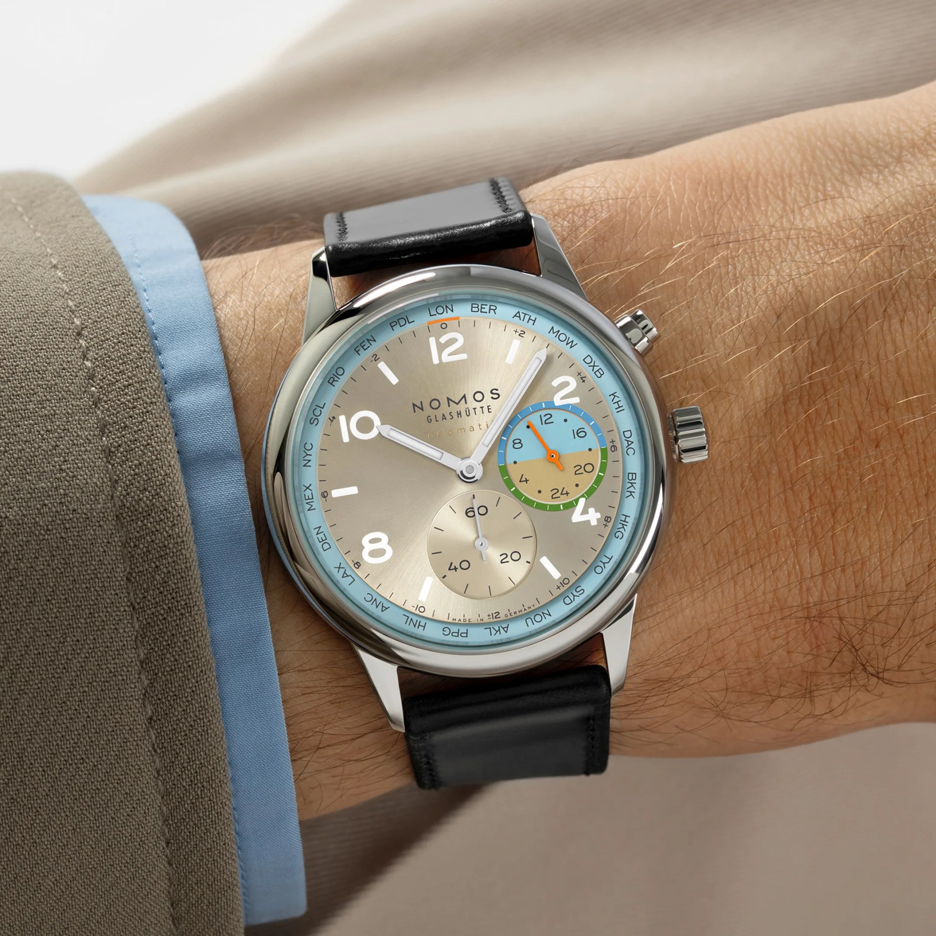 Silver Nomos Glash&uuml;tte watch with black leather strap and multicolor world time dial worn on wrist.
