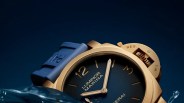 Gold-toned Luminor Marina wristwatch with blue dial and blue rubber strap partially submerged in water.