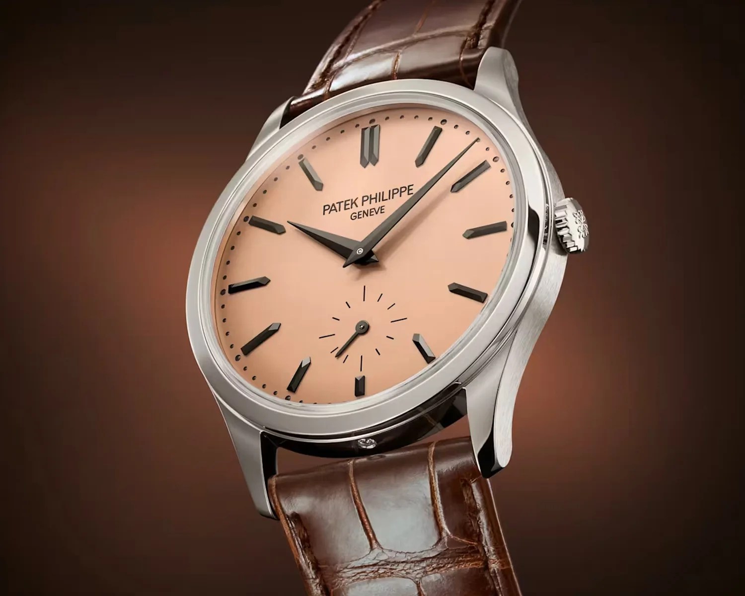 Patek Philippe wristwatch with a salmon dial, black hour markers, silver case, and brown leather strap.