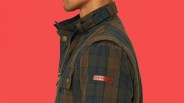 Green and navy plaid jacket with brown leather "Peregrine" patch on the sleeve against a red background.