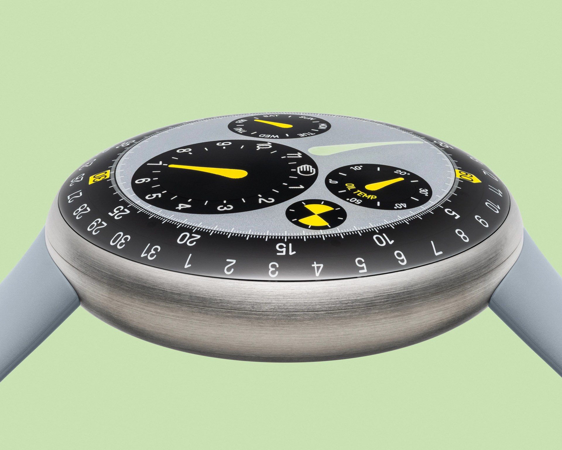 Close-up of a round watch with a brushed metal case, black and gray dial, yellow hands, and light blue strap.