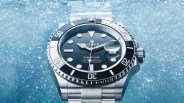 Rolex Submariner watch with black dial and bezel, stainless steel case and bracelet, shown underwater.