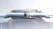 Close-up side view of a polished silver Rolex watch case with a fluted bezel and crown logo on the winding crown.