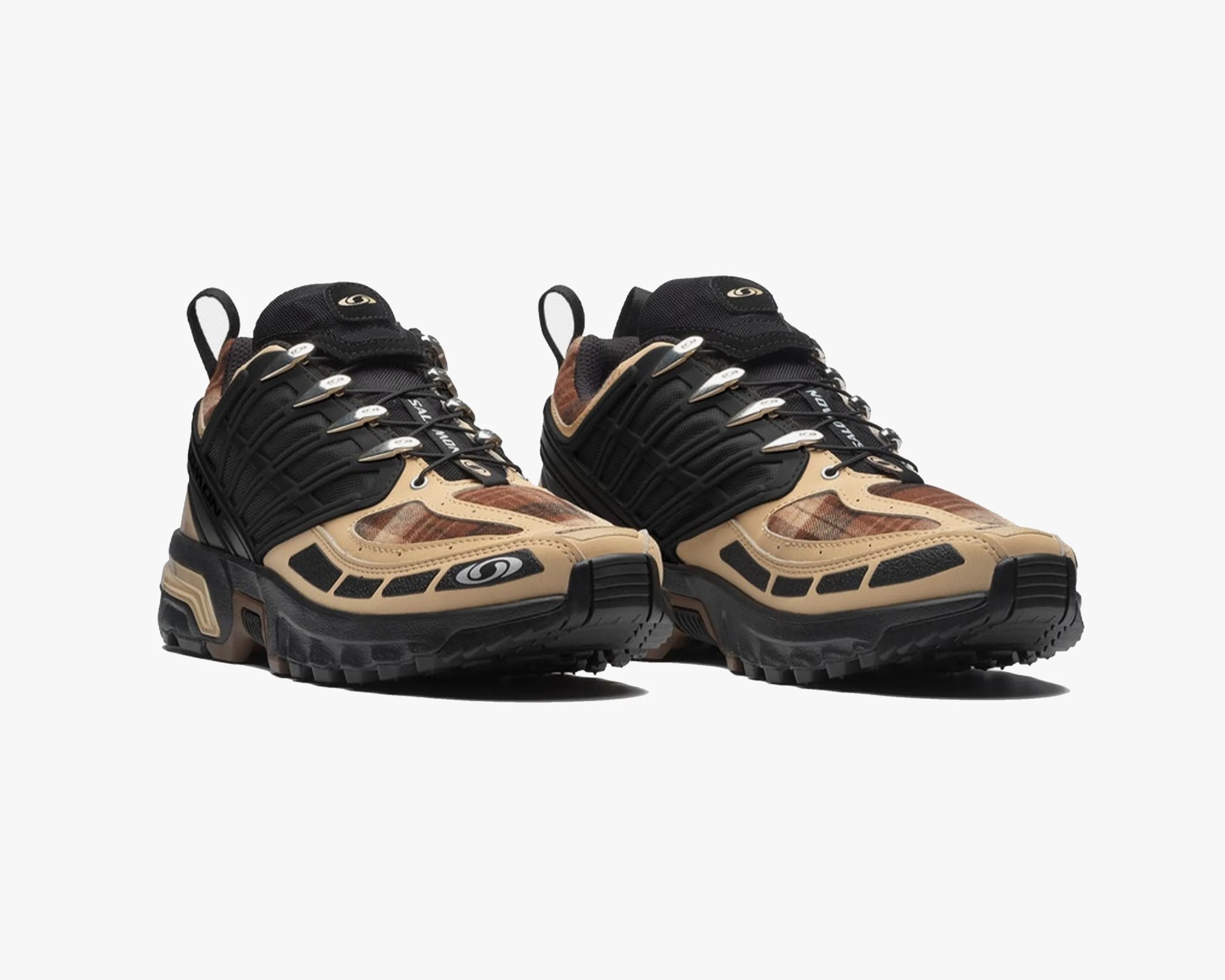 Pair of tan and black trail running shoes with rugged soles and metal lace hooks on a white background.