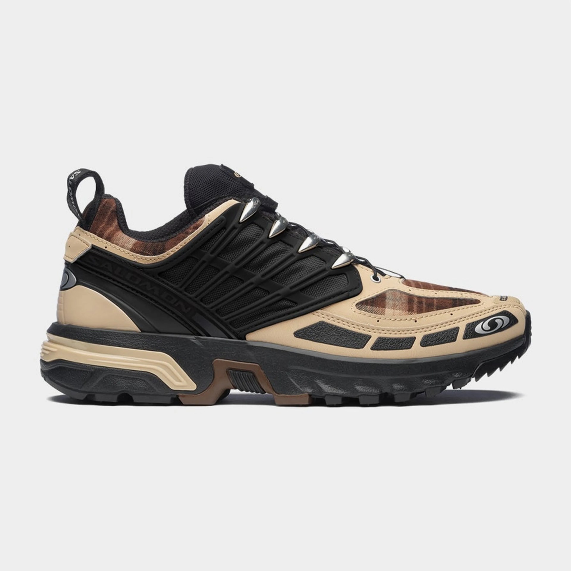 Beige and black trail running shoe with brown plaid accents and rugged sole.