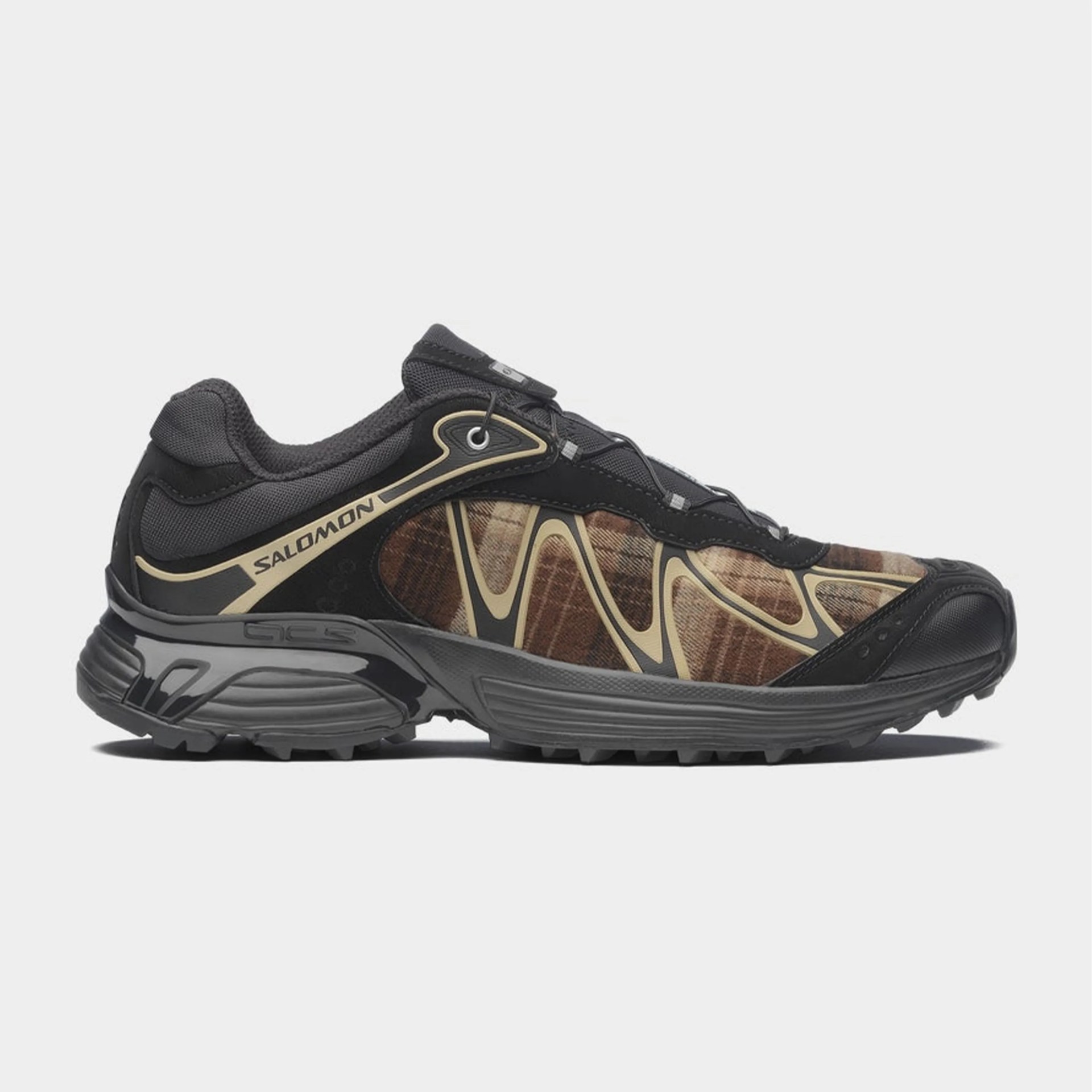 Black and brown Salomon trail running shoe with beige accents and rugged sole.