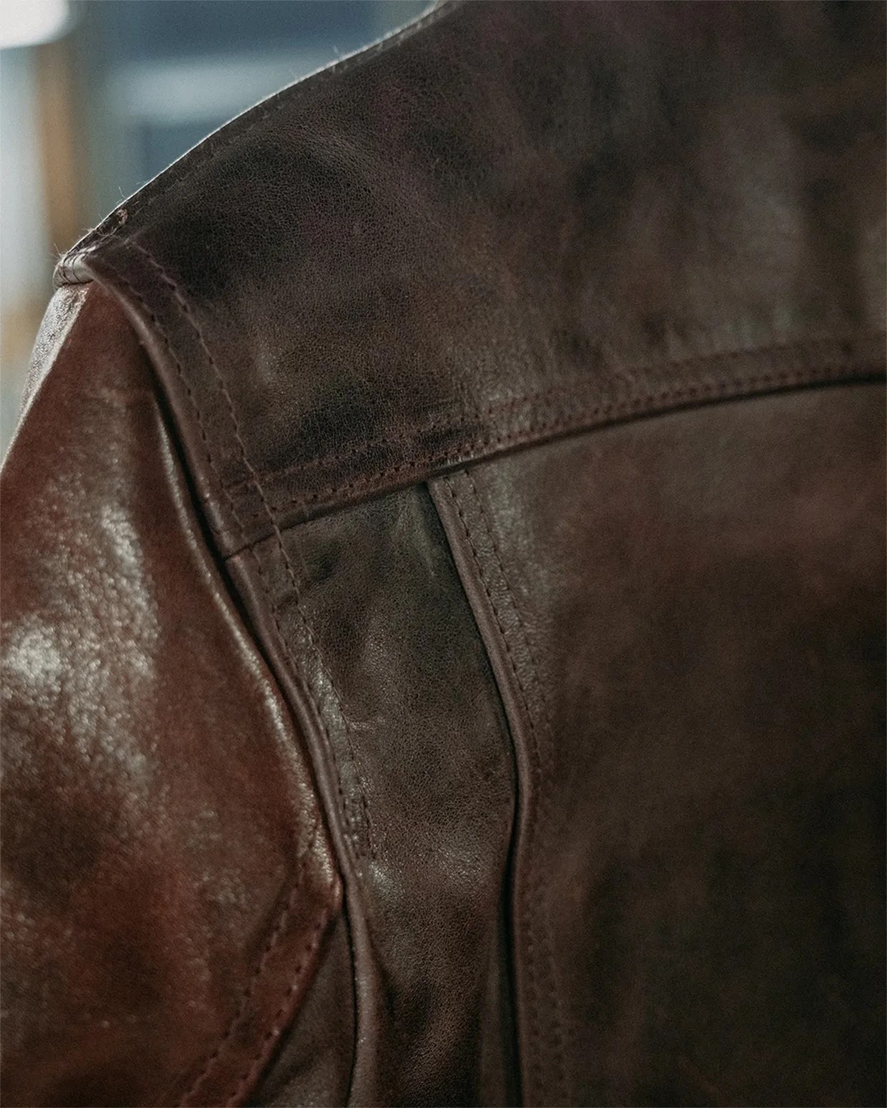 Close-up of dark brown leather jacket showing detailed stitching and texture.