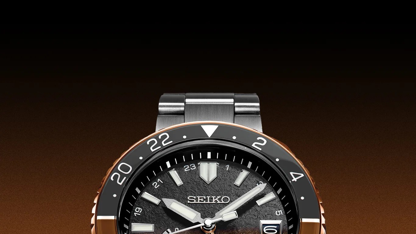 Black Seiko wristwatch with textured dial, silver hour markers, and a two-tone black and rose gold bezel.