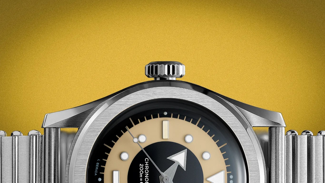 Close-up of a stainless steel wristwatch with a beige and black dial and a metal bracelet against a yellow background.