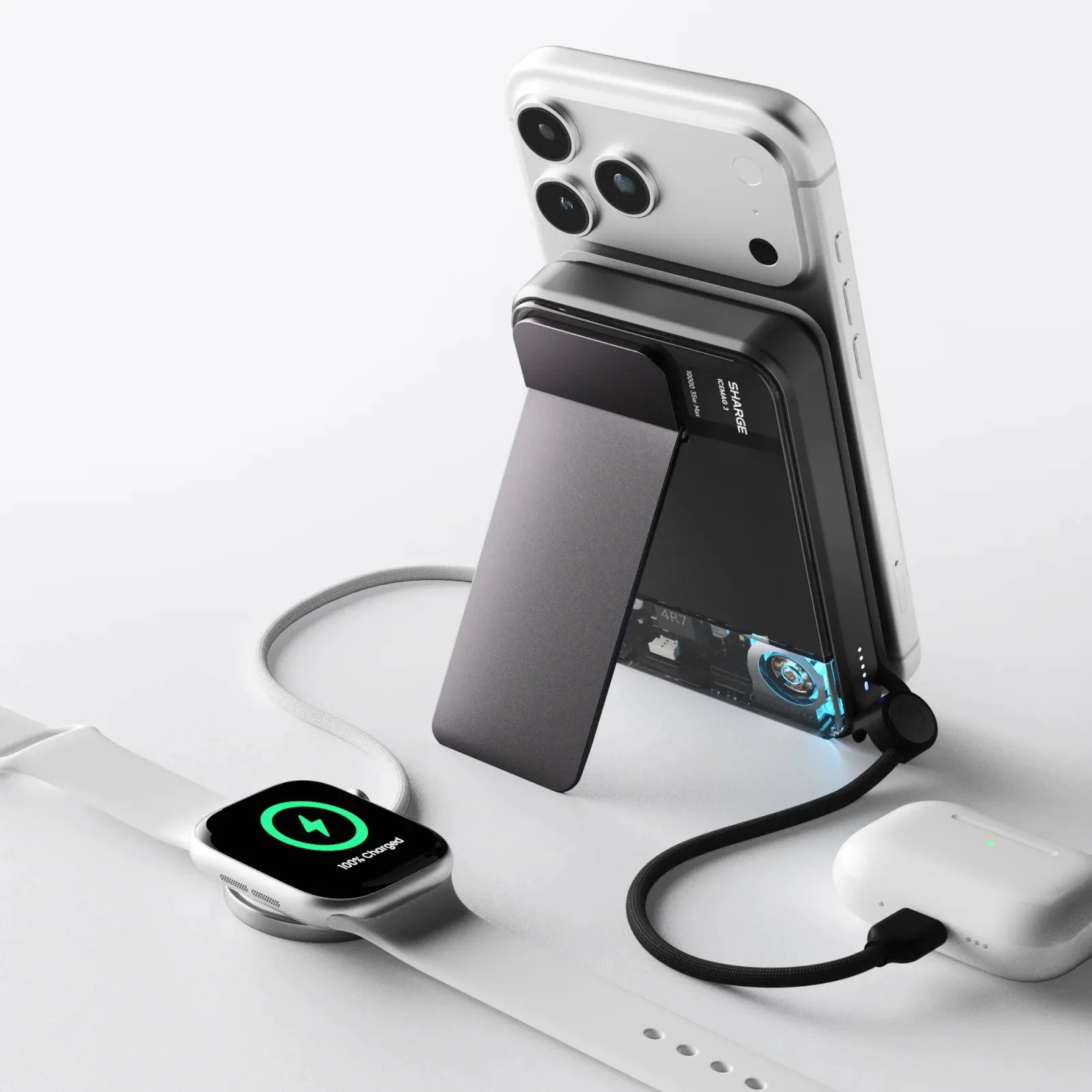 Black wireless charging stand with a silver smartphone, white smartwatch, and white wireless earbuds charging on a white surface.