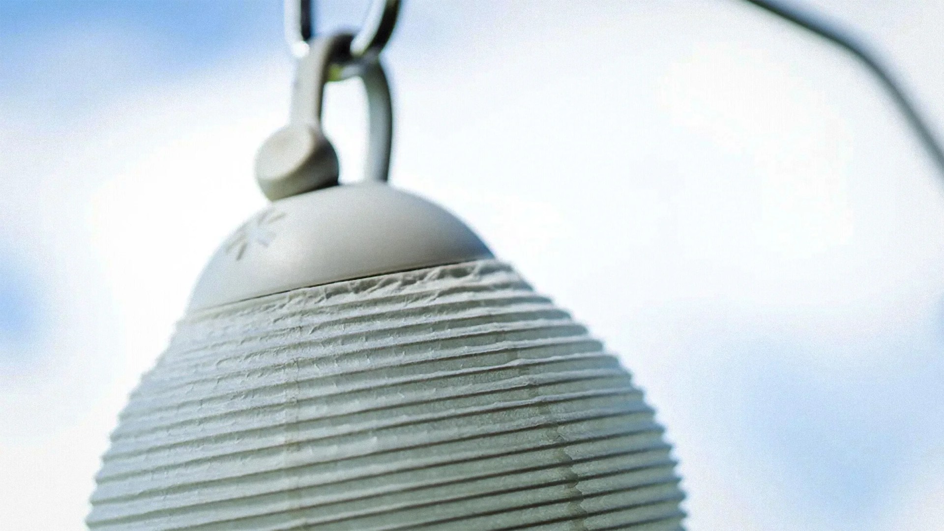Close-up of a white ribbed outdoor hanging lantern against a bright sky.