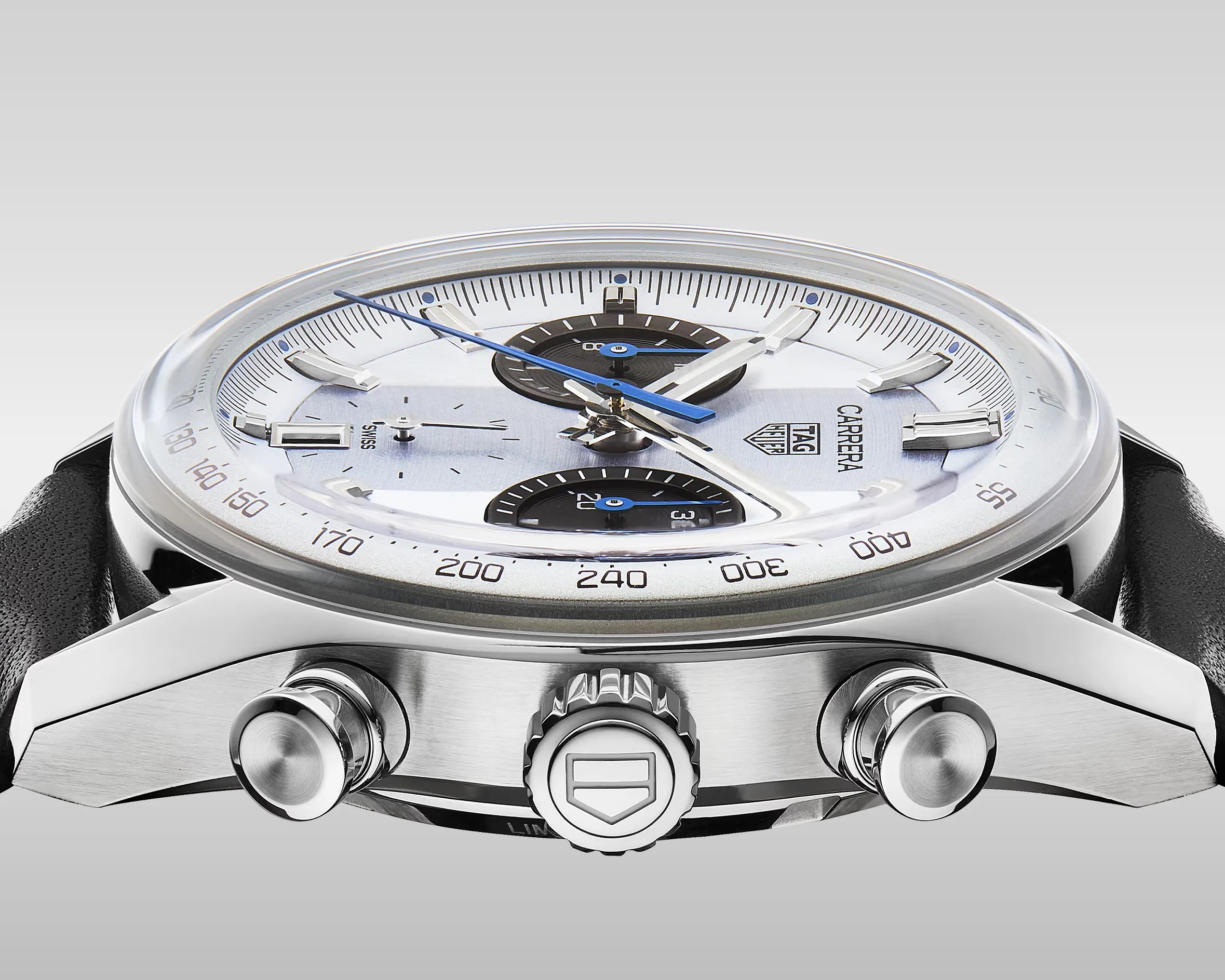 Close-up side view of a TAG Heuer Carrera watch with a silver dial, black subdials, blue and silver hands, and a black leather strap.