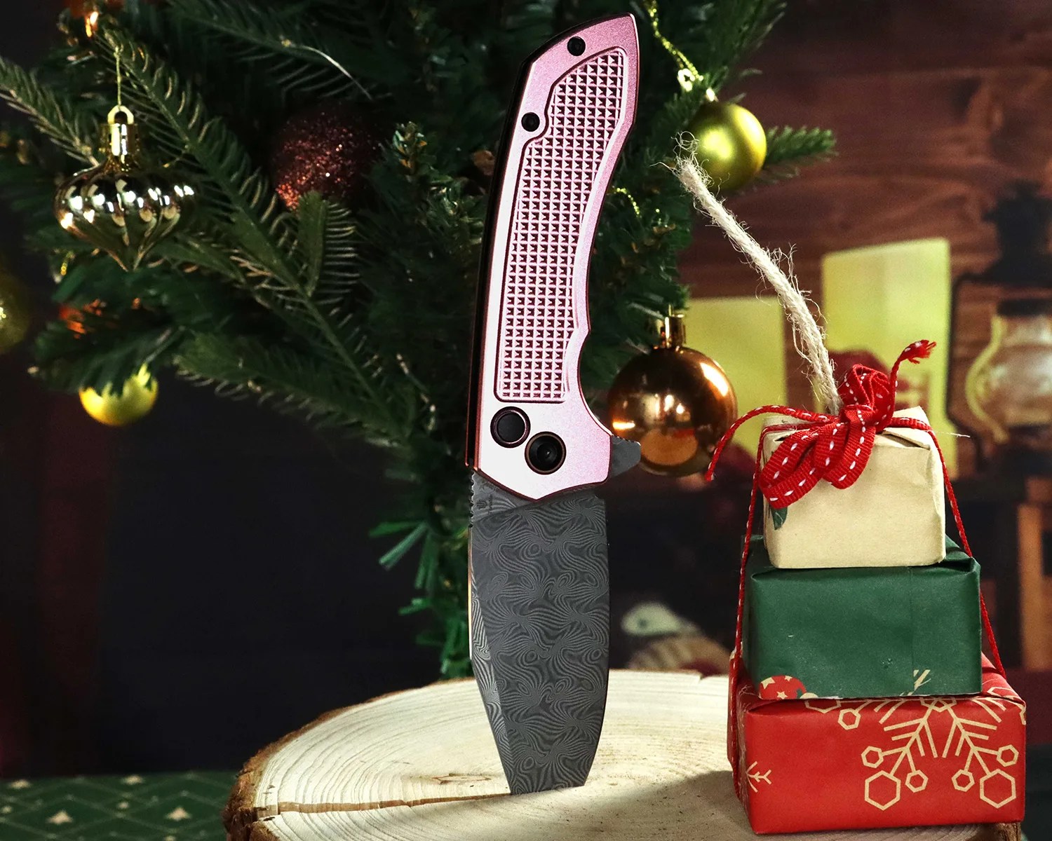 Folding knife with pink textured handle and patterned blade standing on a wooden surface next to stacked wrapped gifts.