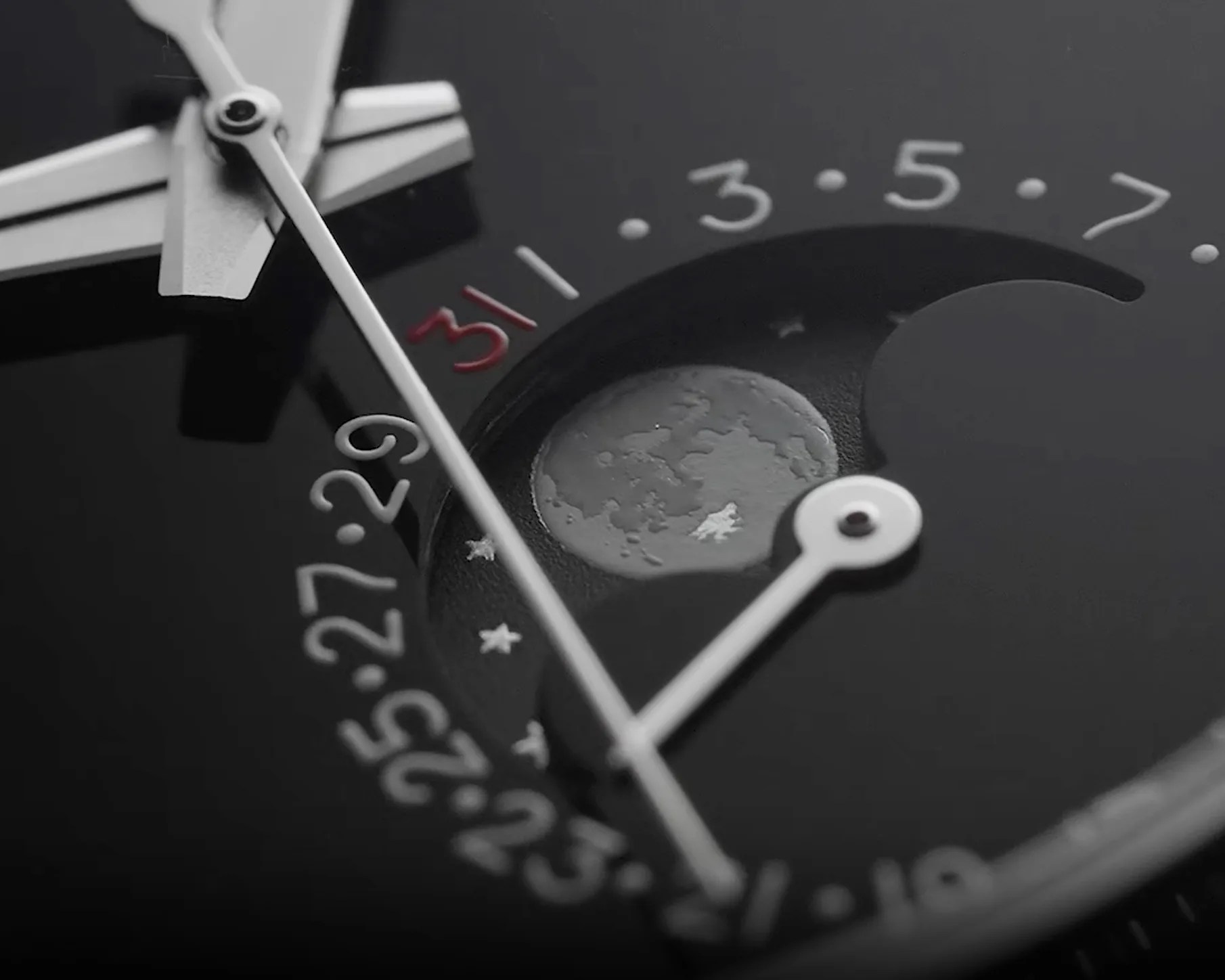 Close-up of a black watch face showing a moon phase indicator and date numbers with a red "31".