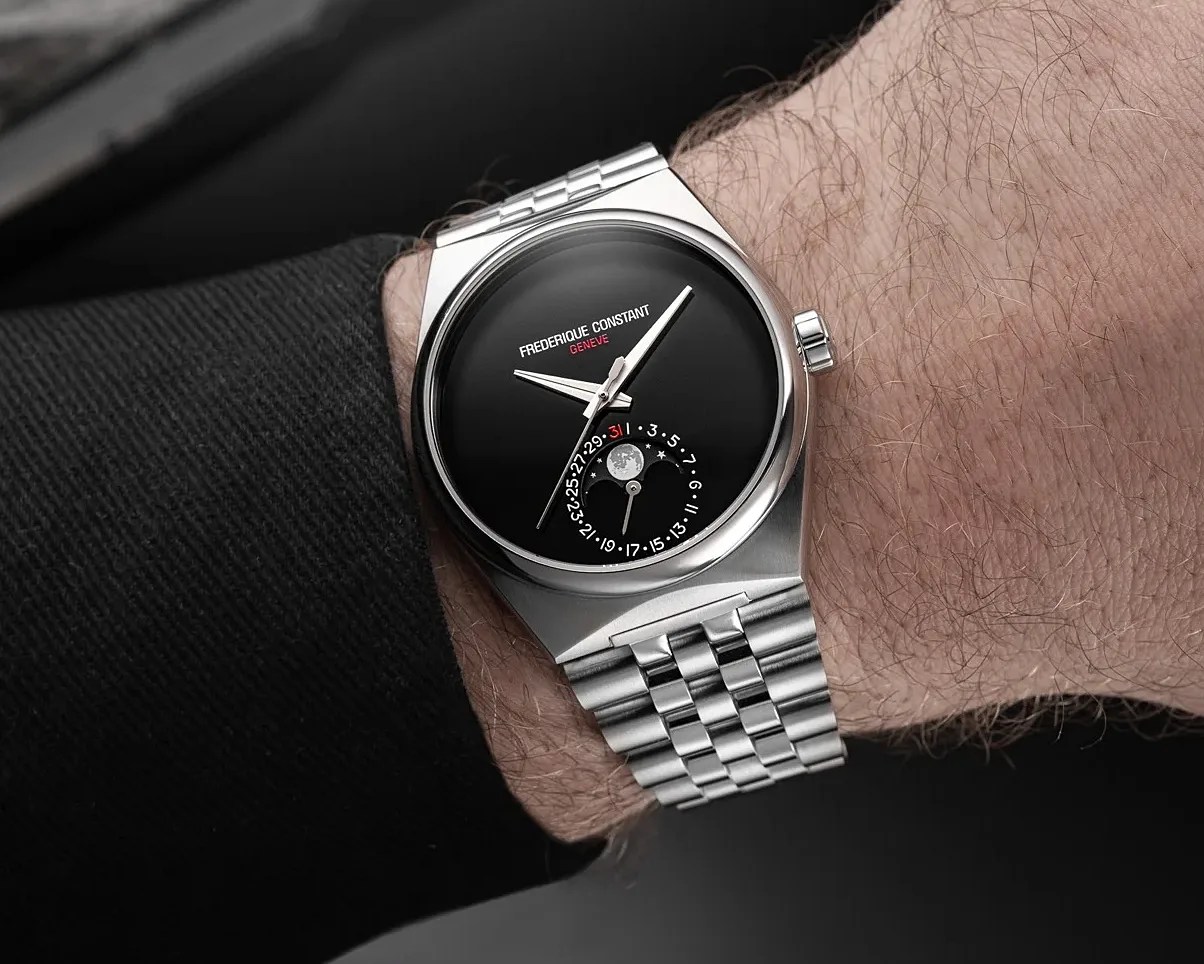 Silver Frederique Constant wristwatch with black dial and moon phase indicator worn on a wrist.