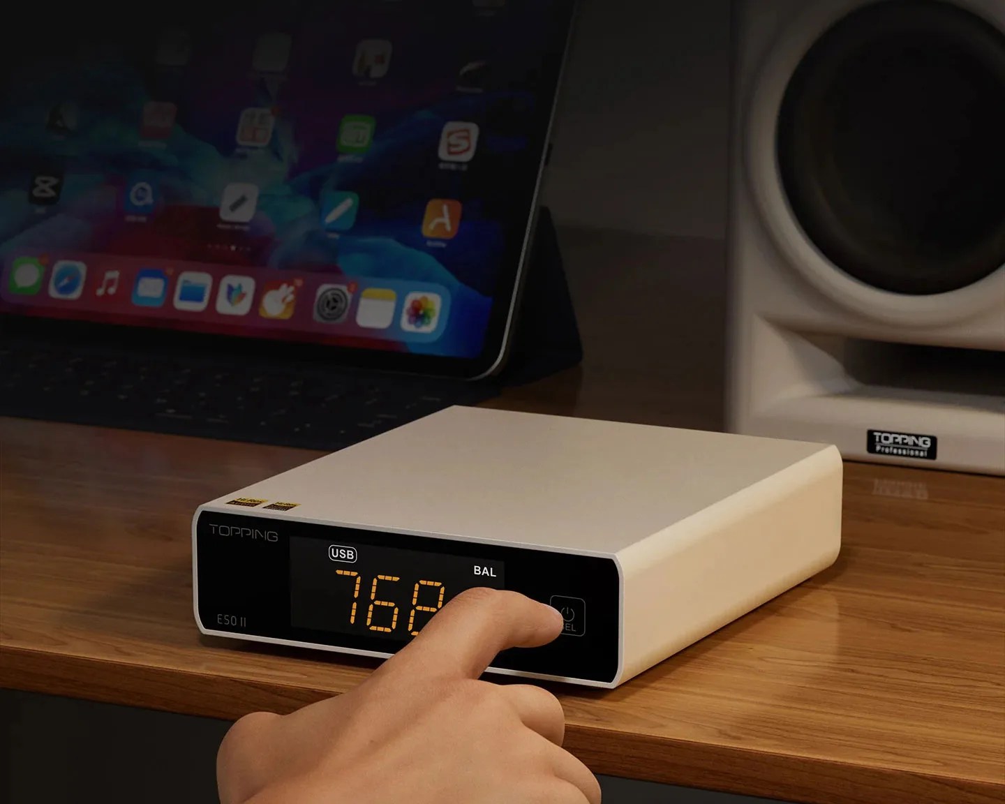 White Topping E50 II audio device with digital display showing "76P" on a wooden desk with a hand pressing a button.