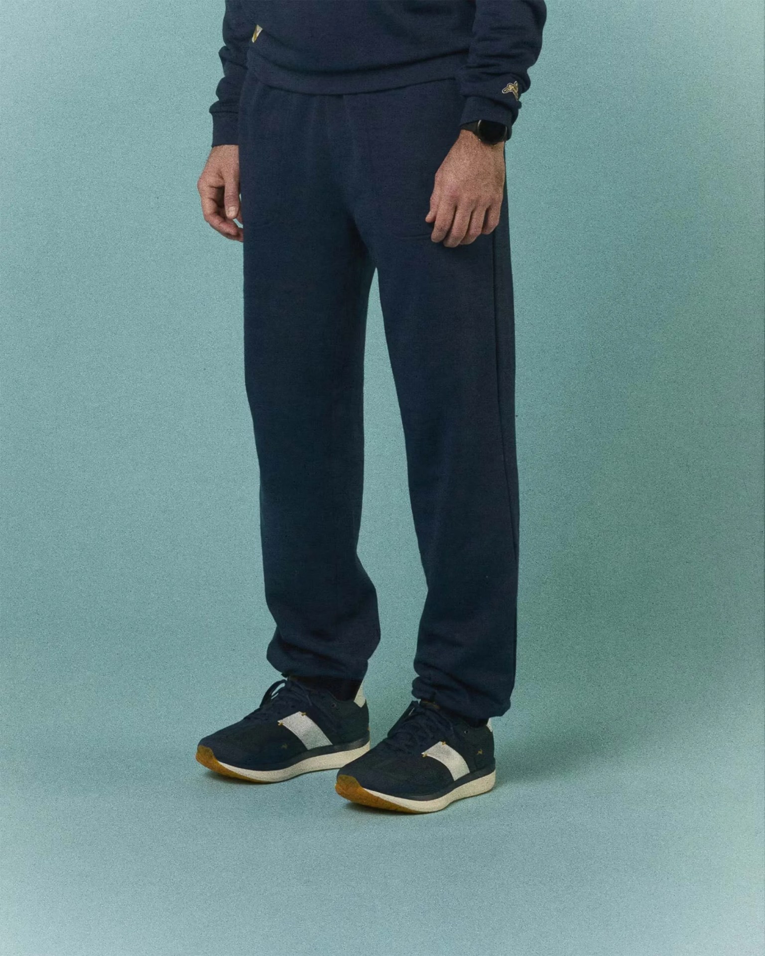 Navy blue sweatpants worn with matching navy sneakers featuring white side panels and gum soles.