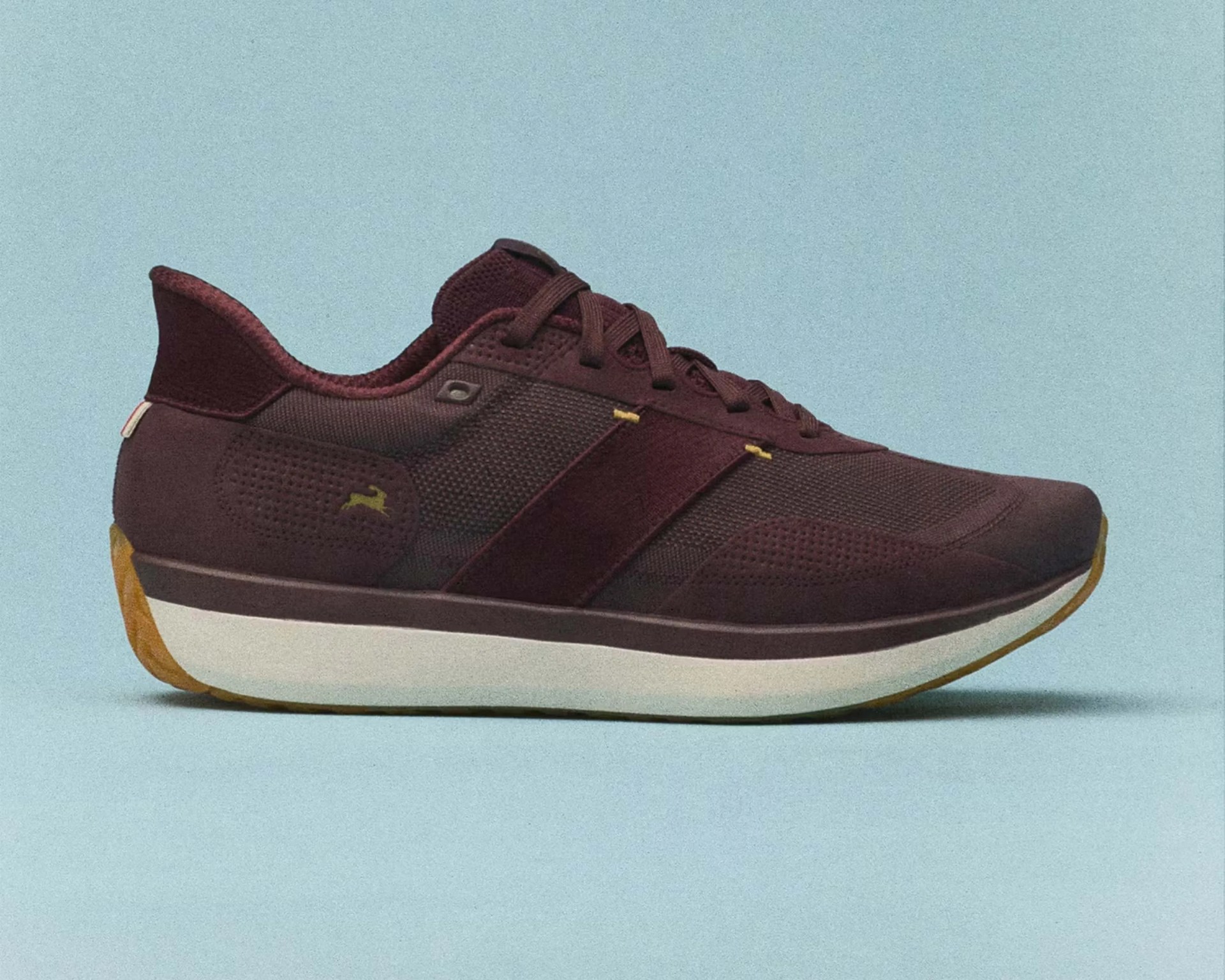Dark maroon athletic sneaker with white midsole and gum outsole on a light blue background.