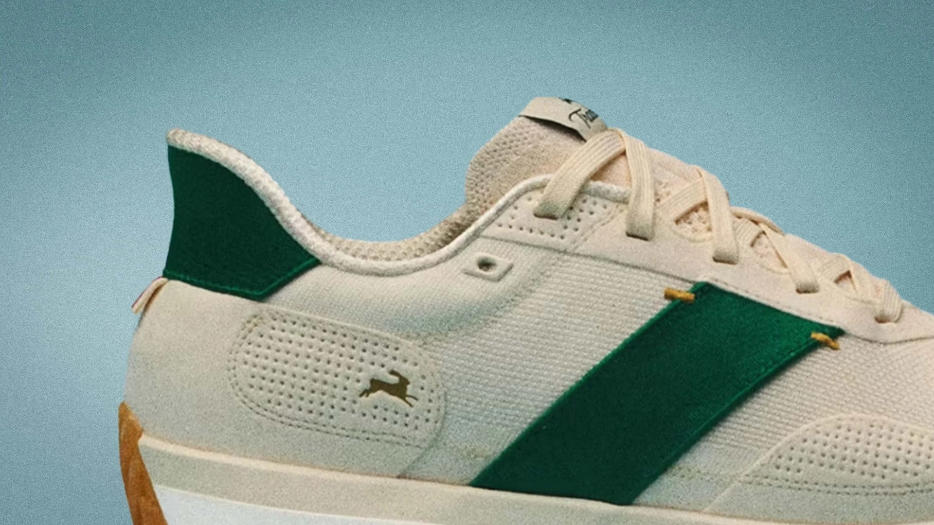 Beige sneaker with dark green stripe and heel tab, perforated detailing, and beige laces.