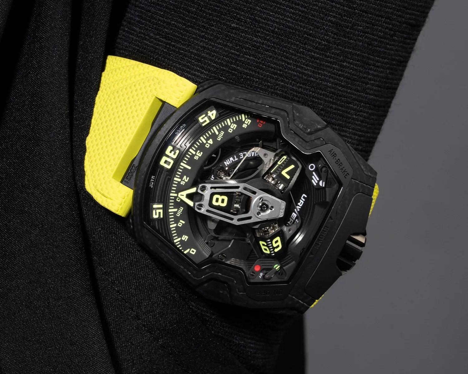 Black and yellow futuristic wristwatch with a complex dial and mechanical components visible, worn on a wrist.