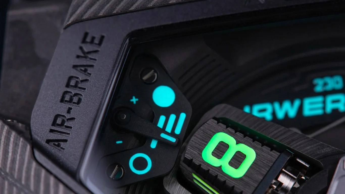 Close-up of a black watch dial with illuminated blue and green adjustment indicators.