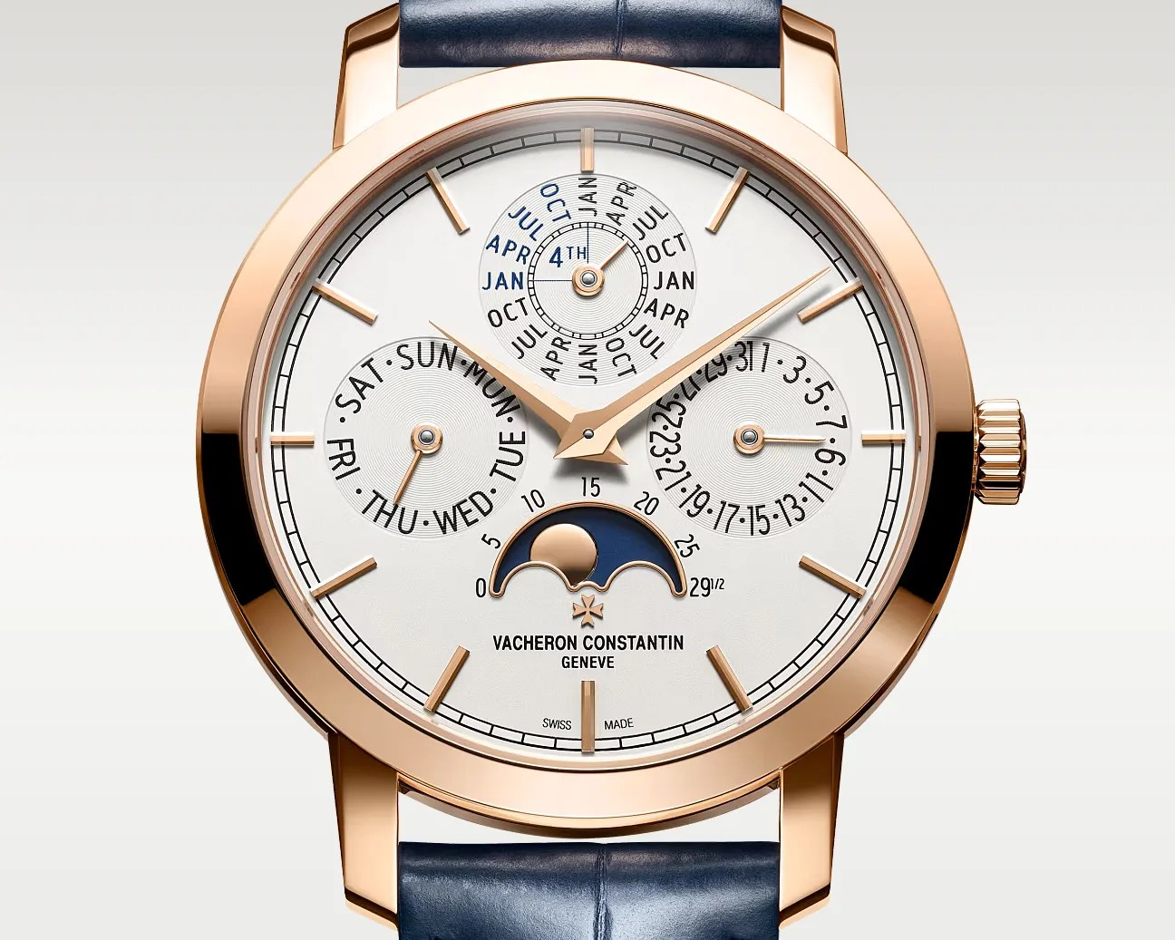 Rose gold Vacheron Constantin wristwatch with white dial, blue leather strap, moon phase, day, date, and month subdials.