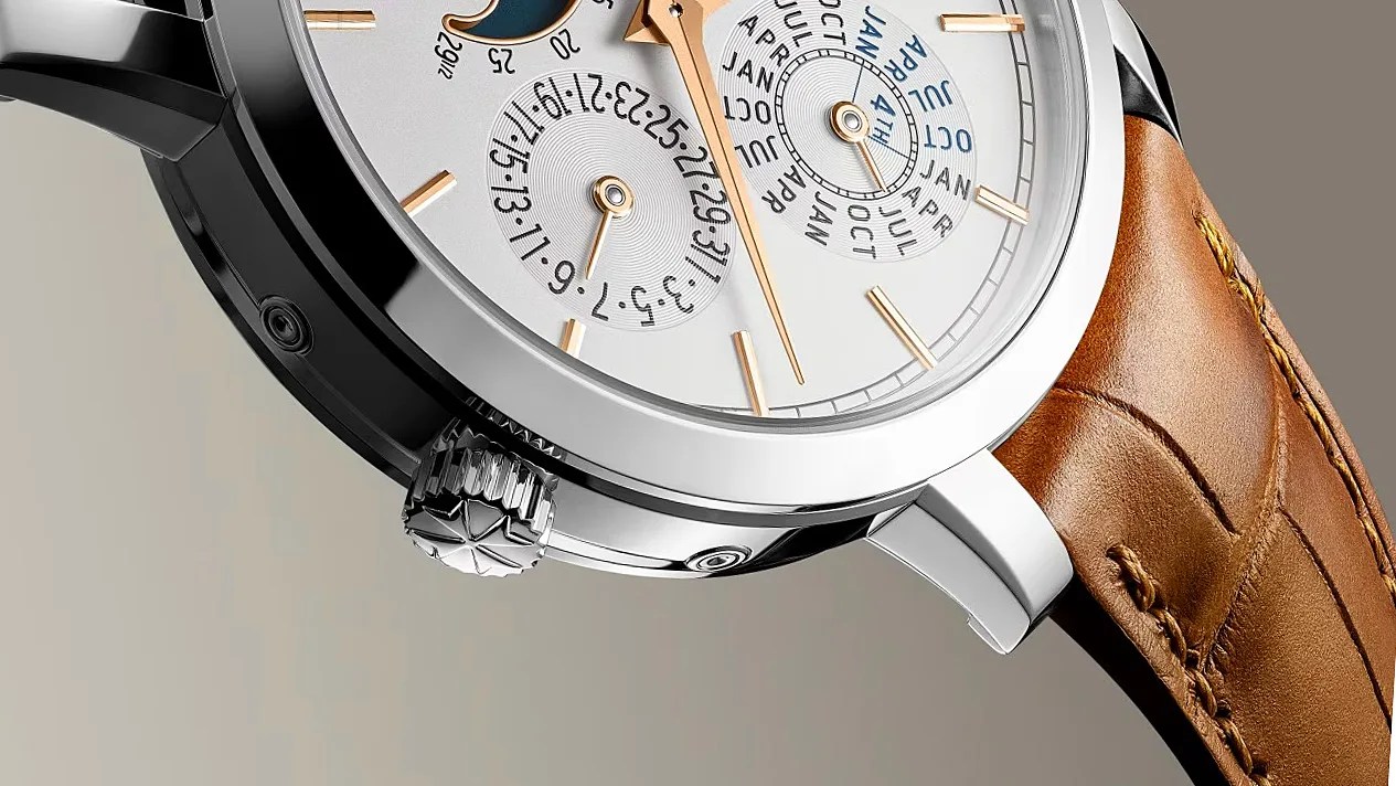 Close-up of a silver watch with gold hands and markers, featuring subdials and a brown leather strap.
