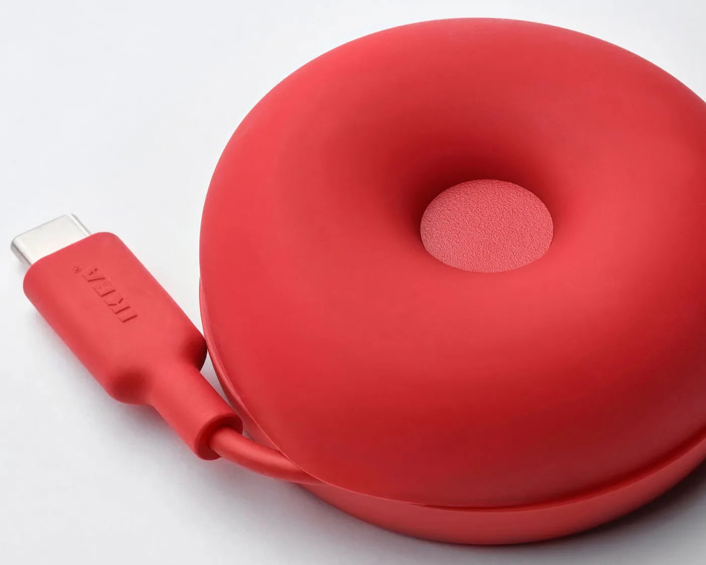 Red circular device with a USB-C connector and a central textured button.