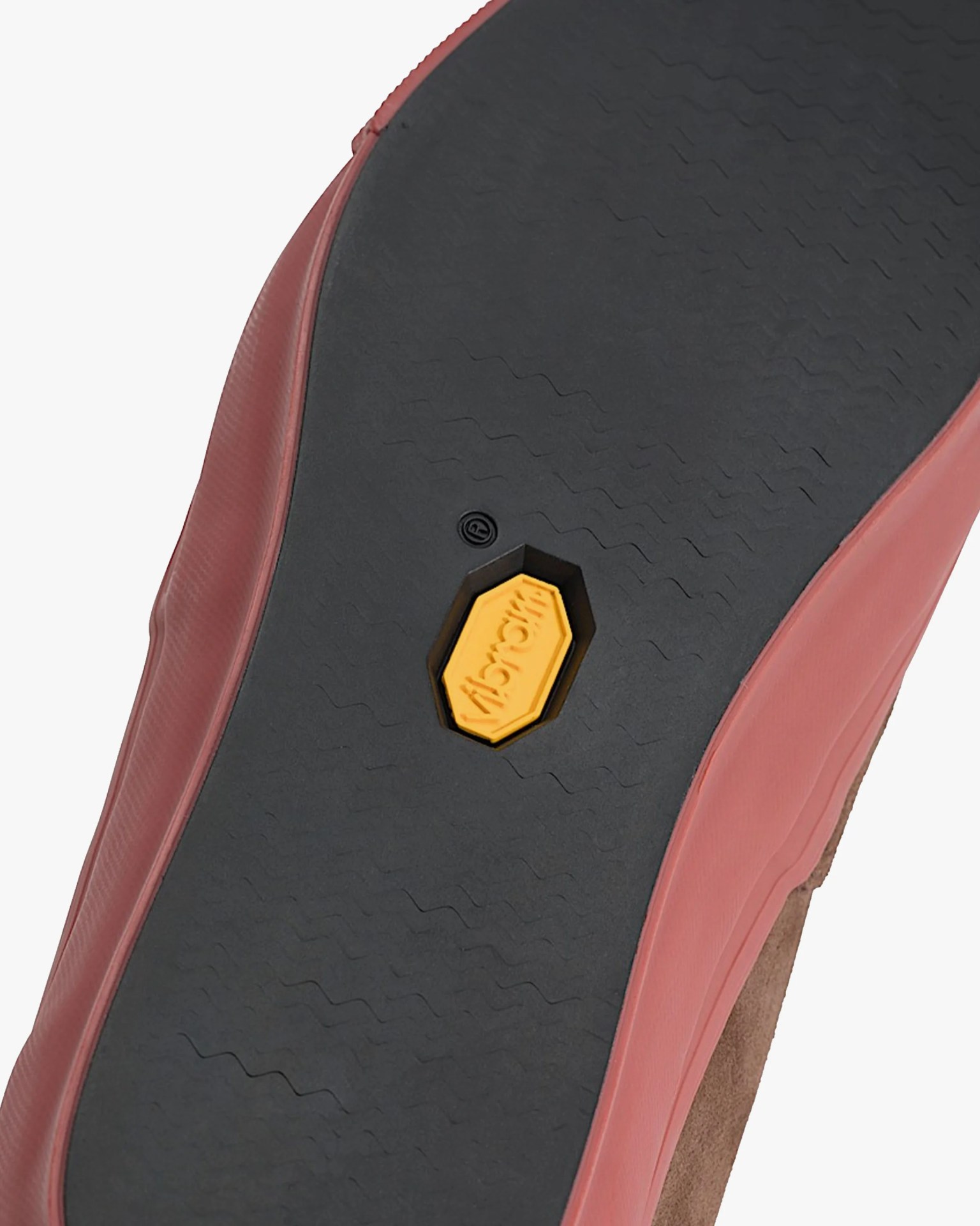Close-up of a shoe sole with a black rubber bottom, red sides, and a yellow Vibram logo in the center.