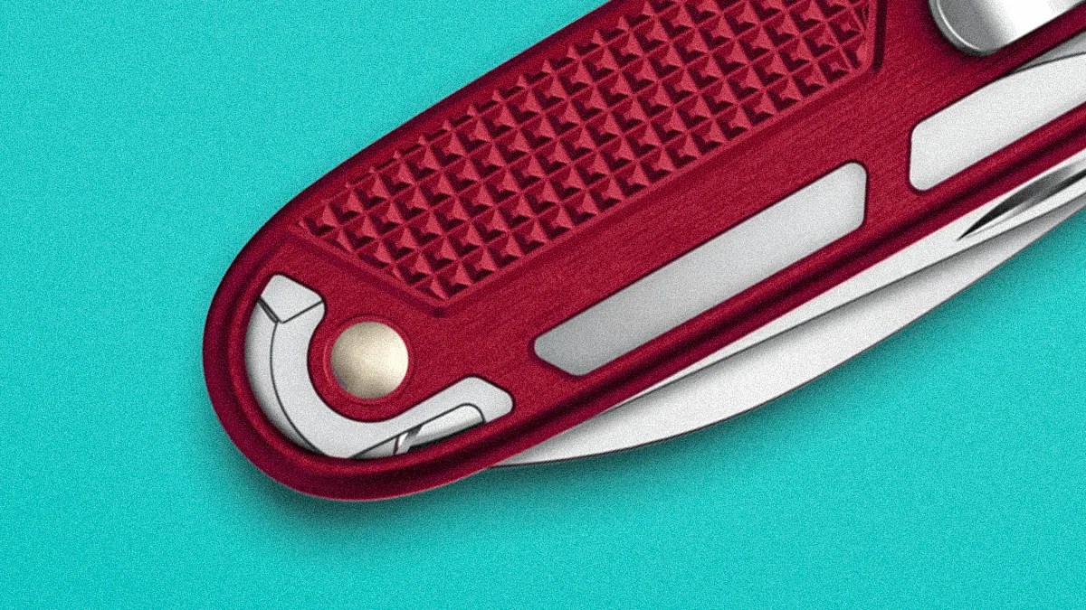 Close-up of a red Swiss Army knife handle with textured grip and partially visible blade on a turquoise background.
