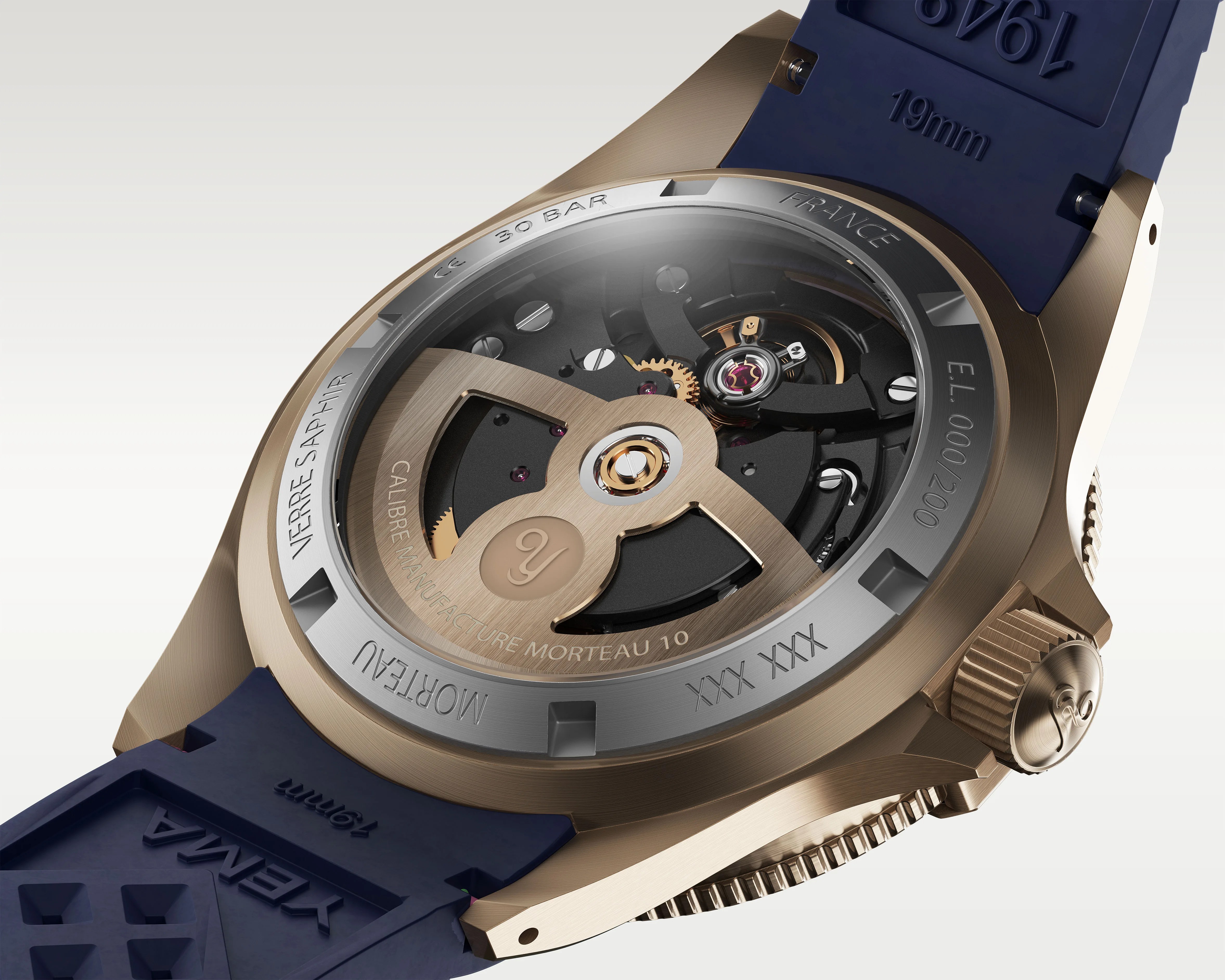 Close-up of the back of a bronze wristwatch with visible mechanical movement and a blue rubber strap marked "XENA 19mm.