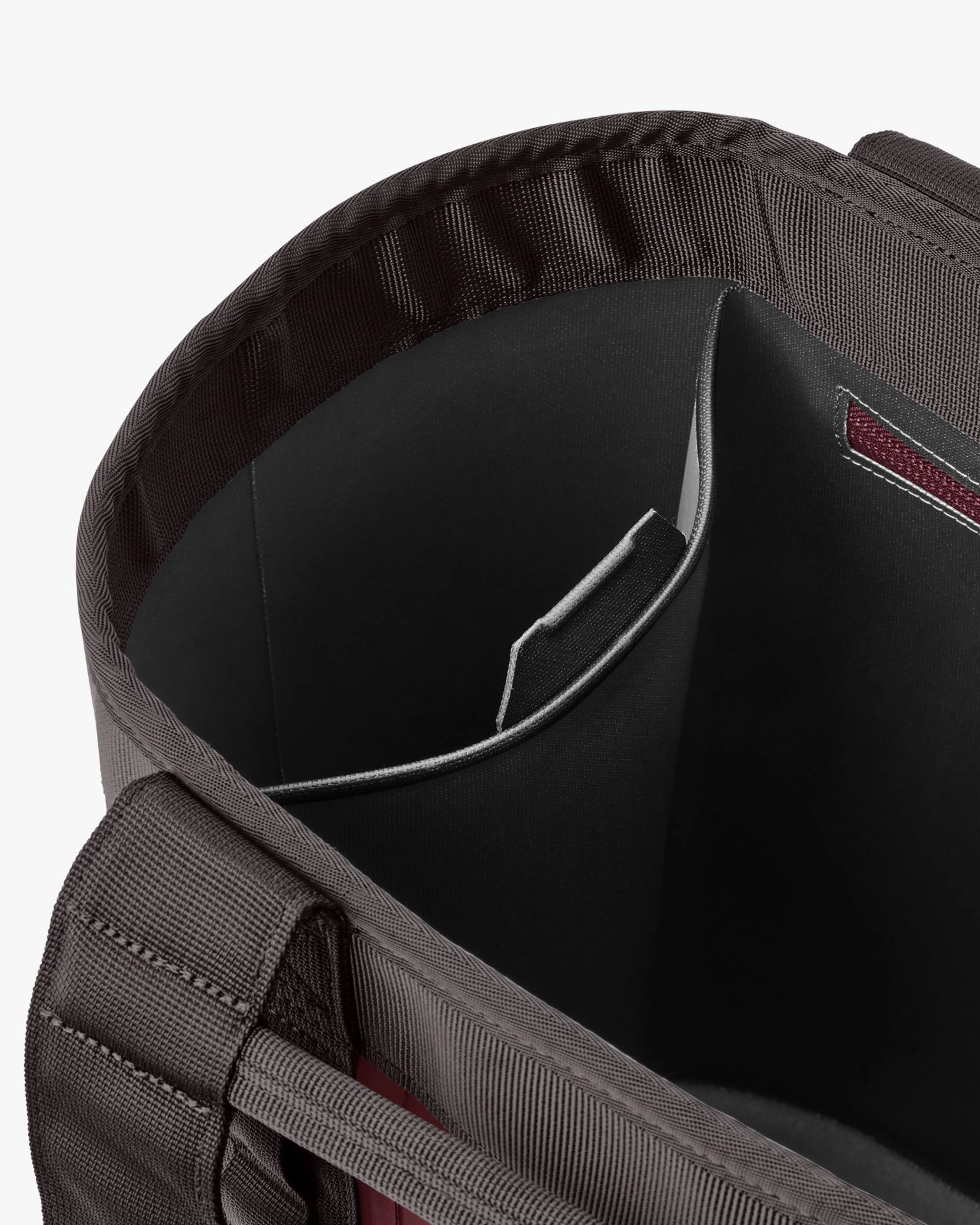 Close-up of a black and dark gray fabric bag interior with a padded divider and reinforced stitching.