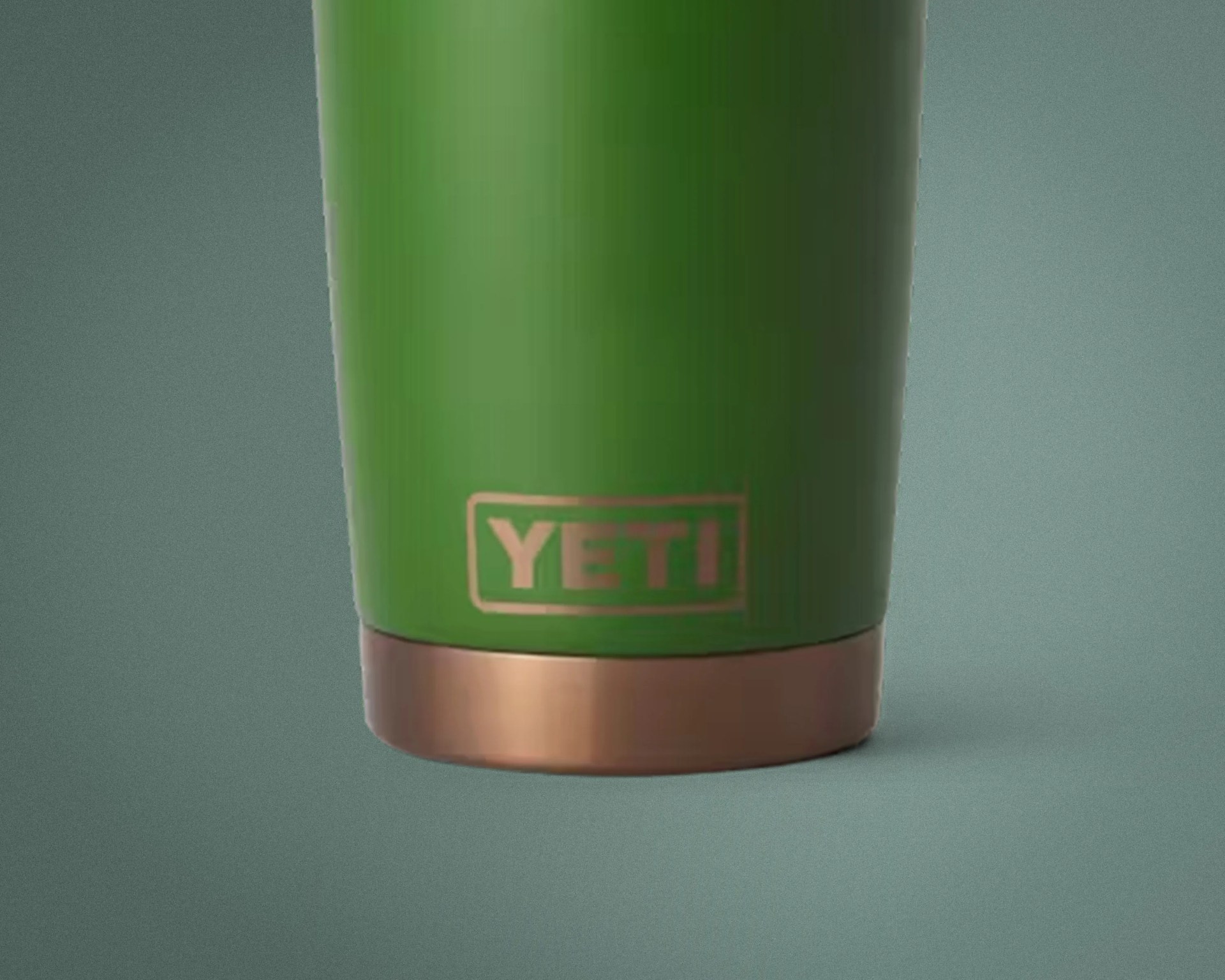 Green YETI tumbler with copper-colored base on a gray surface.