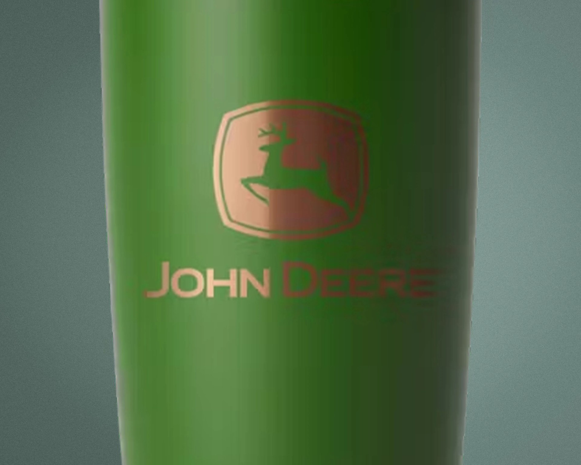 Green cylindrical object with a gold John Deere logo featuring a leaping deer.