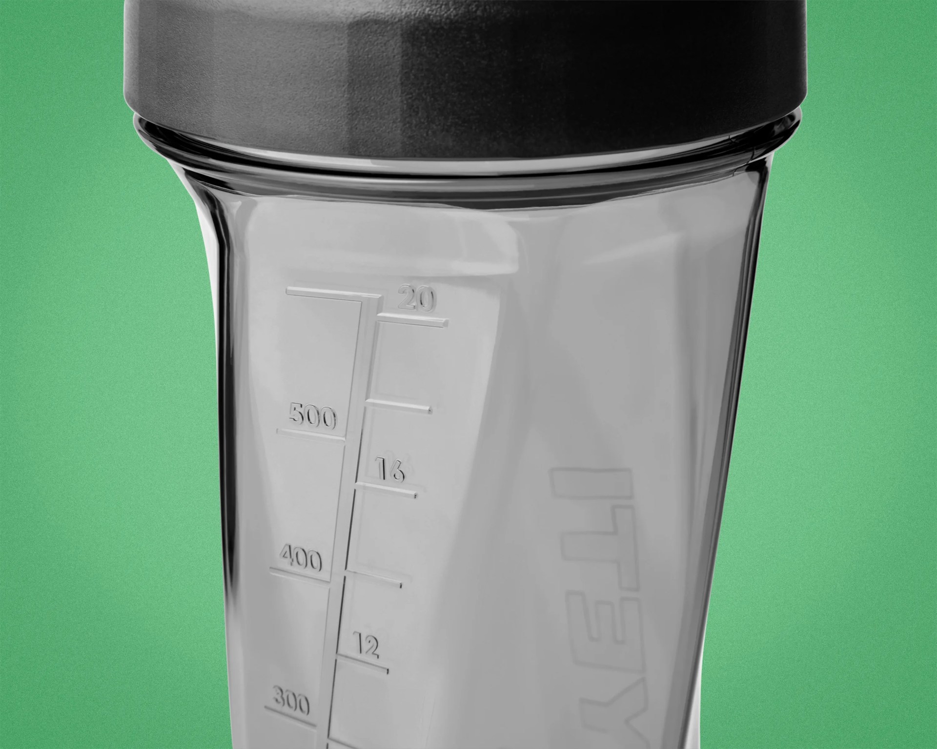 Clear plastic blender jar with black lid and measurement markings up to 500 ml against a green background.