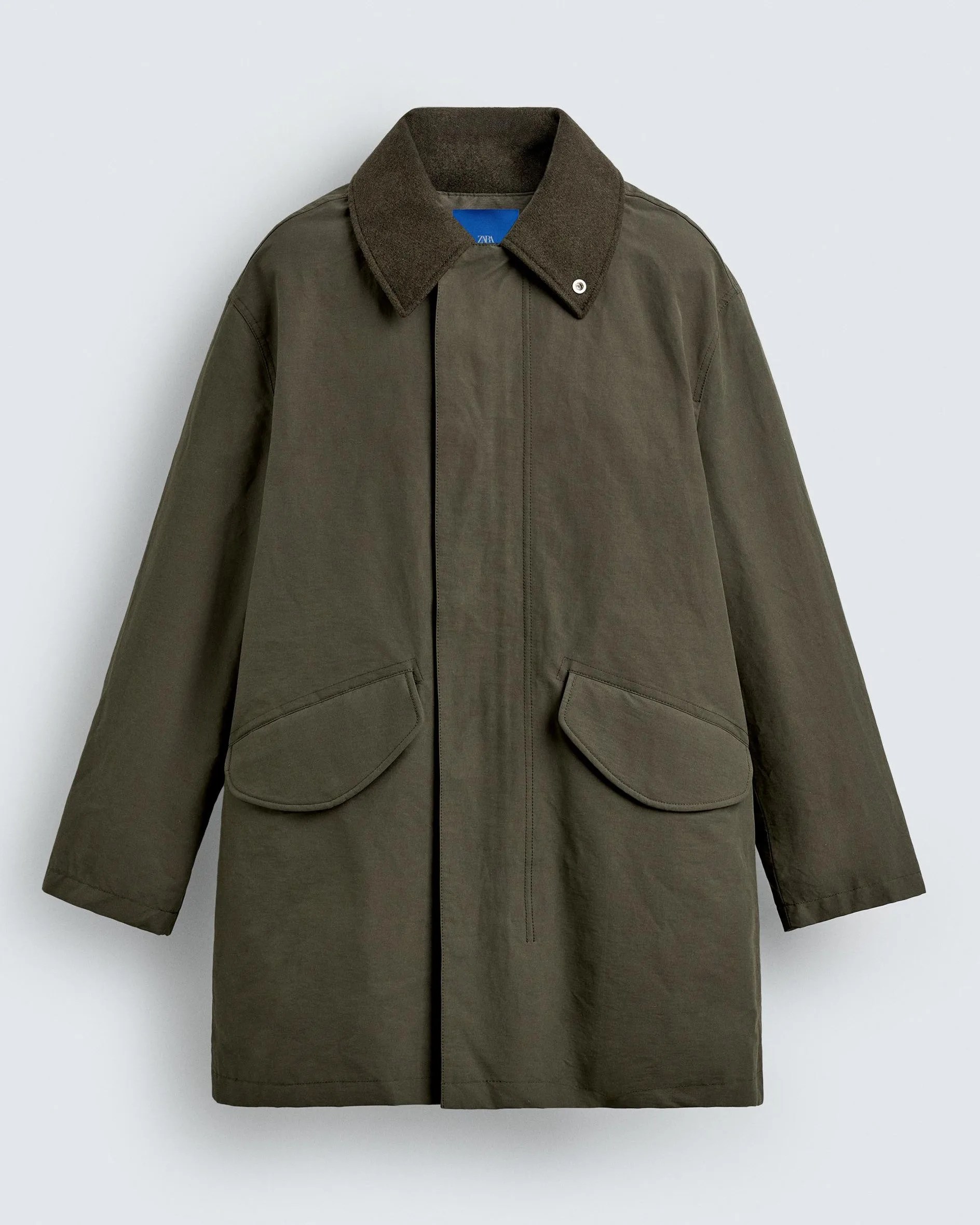 Olive green long coat with dark brown collar and flap pockets on front.