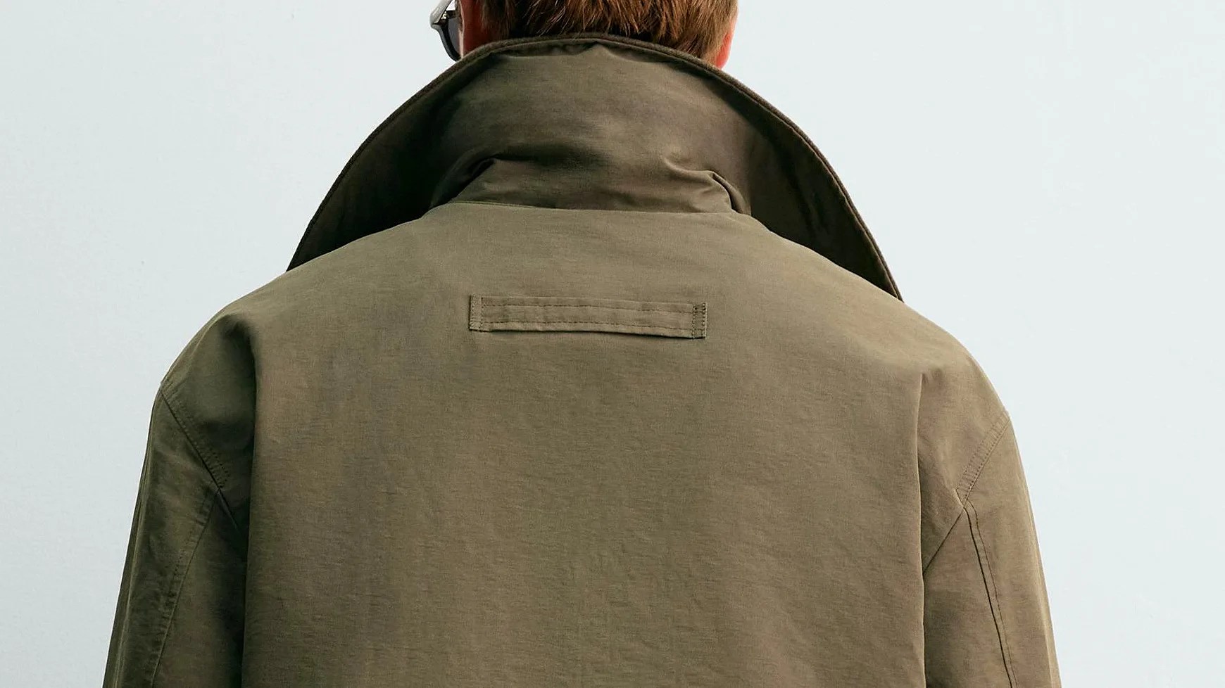 Olive-green jacket with a raised collar viewed from the back.
