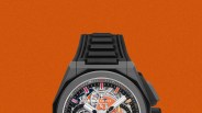 Black Zenith El Primero wristwatch with a skeleton dial, orange accents, and a black rubber strap on an orange background.