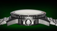 Close-up of a stainless steel watch case with a ridged bezel and a crown featuring a crosshair symbol, against a green background.