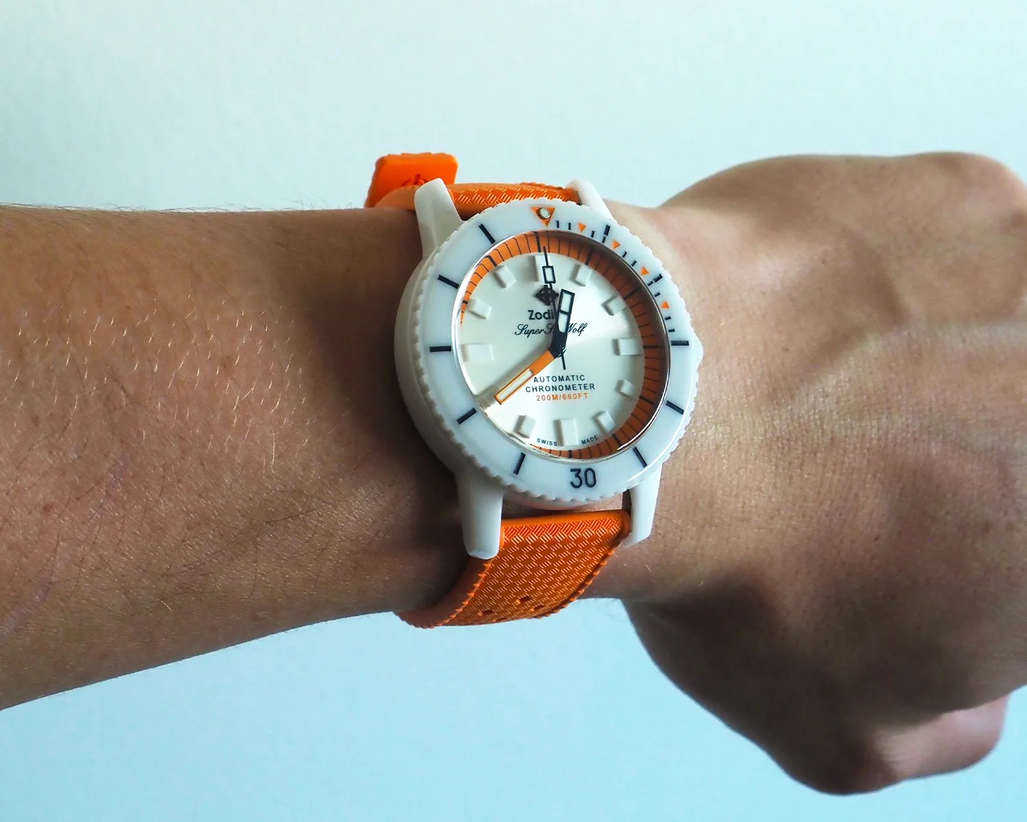 White Zodiac Super Sea Wolf automatic chronometer watch with orange accents and strap on a wrist.