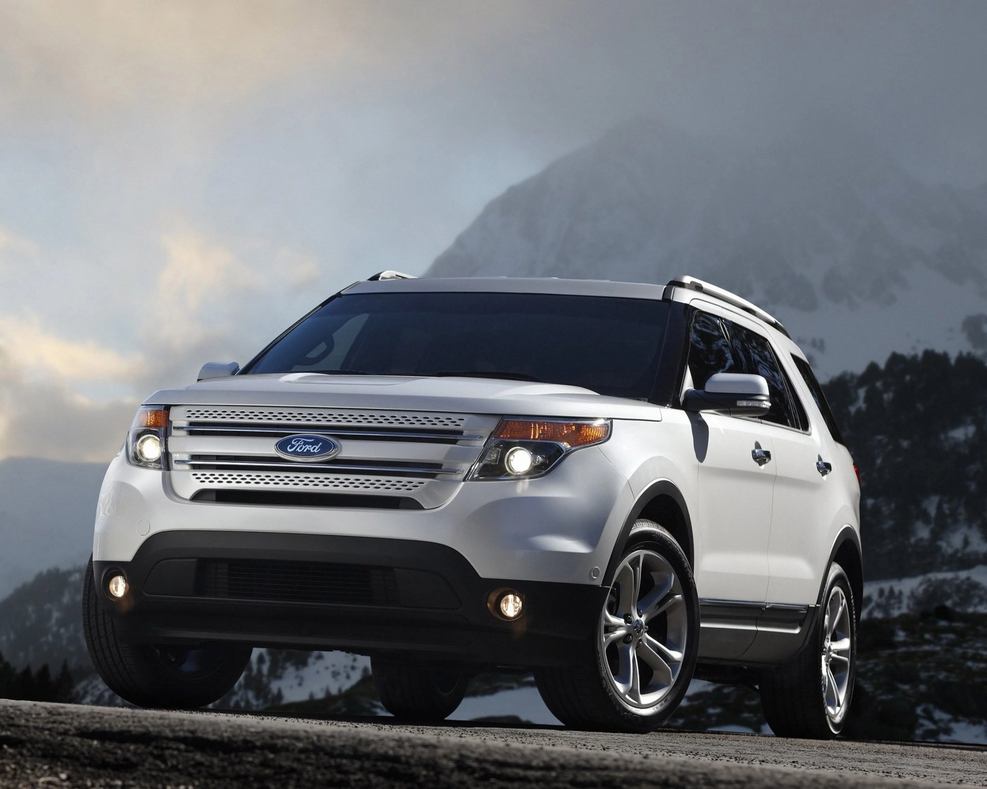 White Ford SUV with chrome grille and alloy wheels parked on a mountain road with foggy peaks in the background.