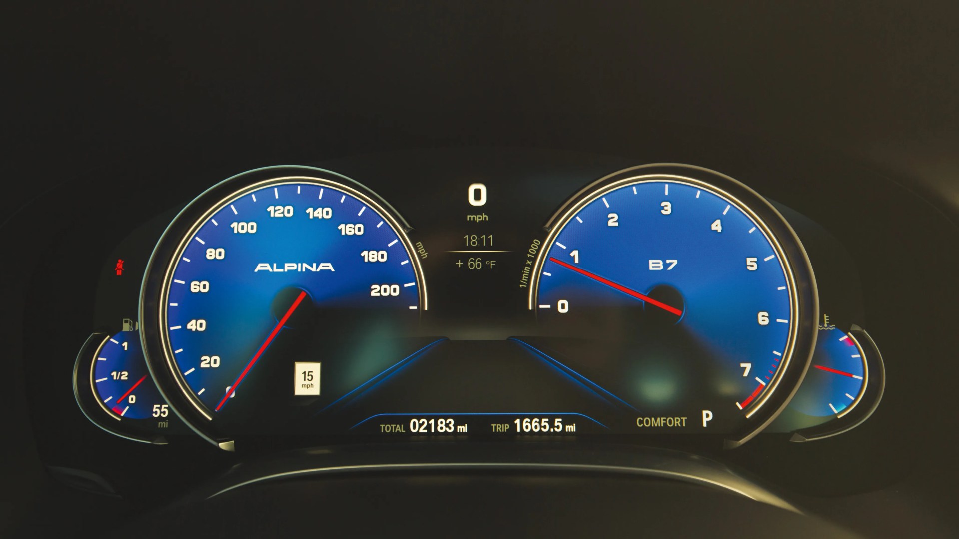Blue Alpina B7 car dashboard with speedometer, tachometer, fuel, and temperature gauges showing 0 mph and 2183 total miles.