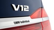 Close-up of a dark blue BMW car rear with V12 and BMW Individual badges near a red tail light.