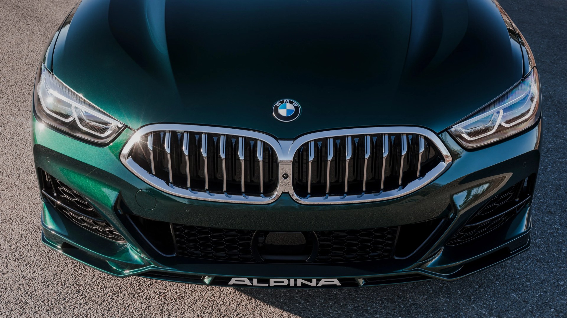 Front view of a dark green BMW Alpina car showing the kidney grille, headlights, and Alpina logo on the front lip.