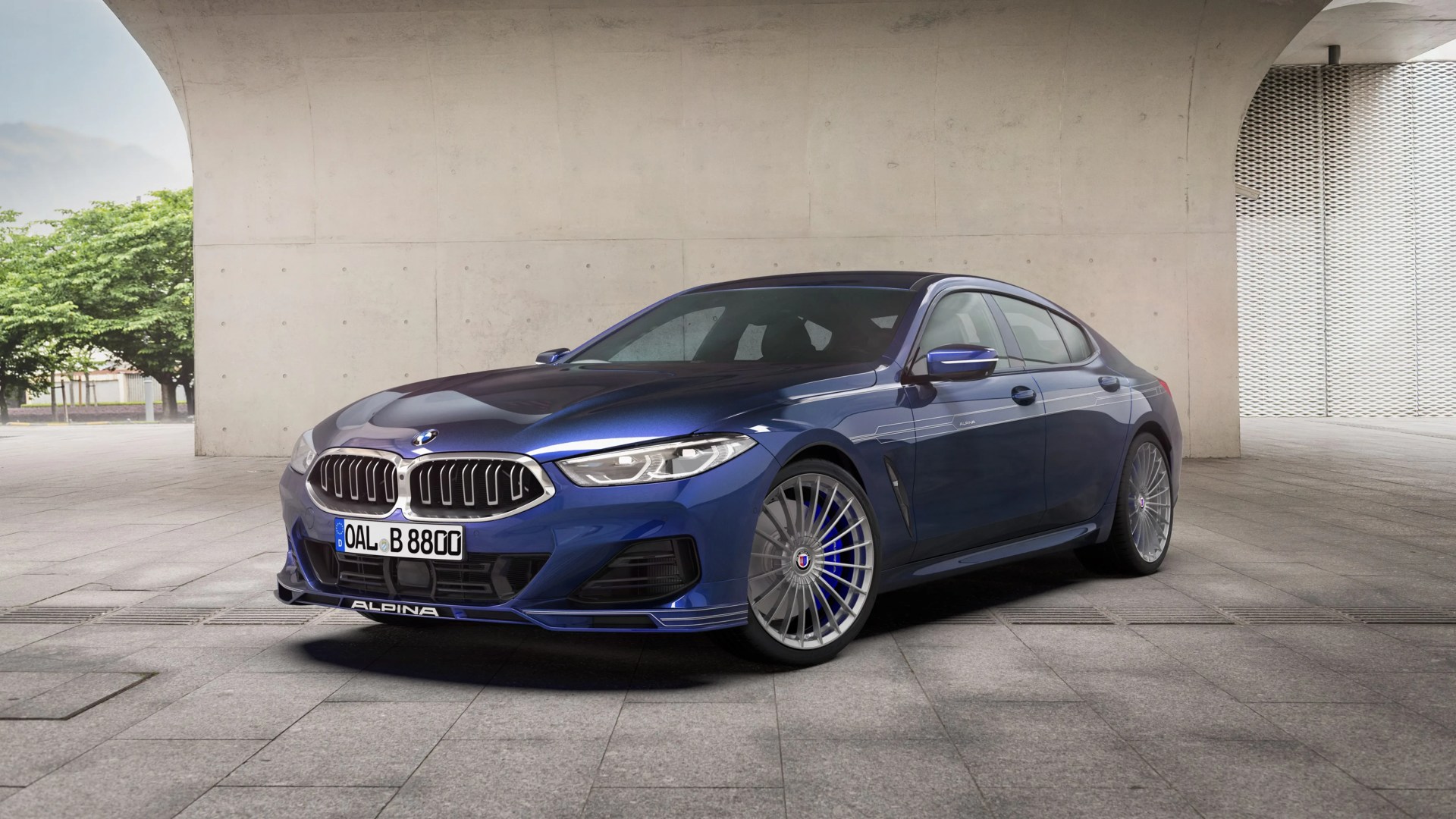 Blue Alpina luxury sedan with silver multi-spoke wheels parked under a concrete archway.