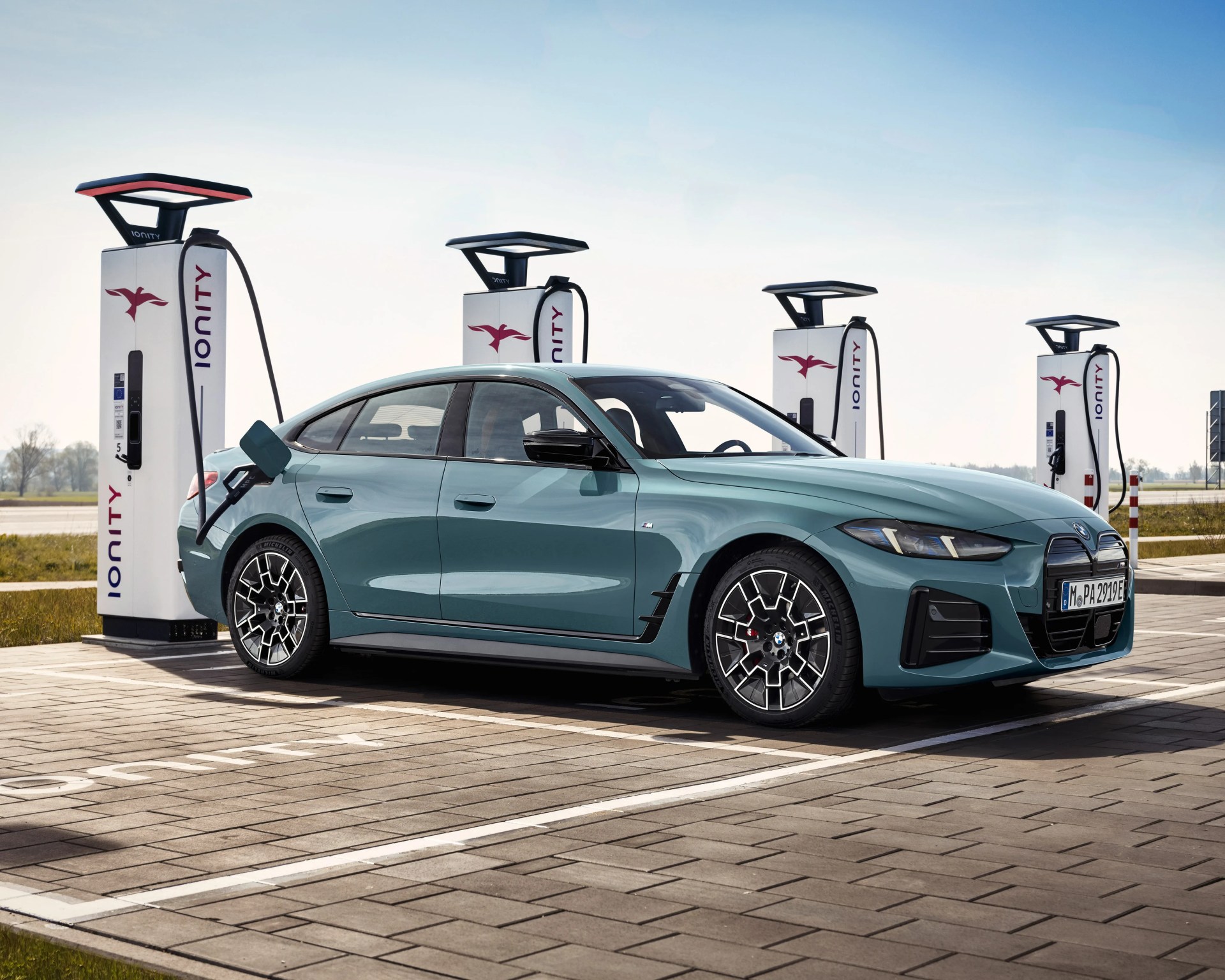 Blue BMW electric sedan charging at an Ionity station with four white charging units.