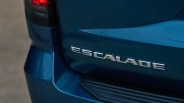 Chrome "ESCALADE" badge on the rear of a blue vehicle near the taillight and bumper step.
